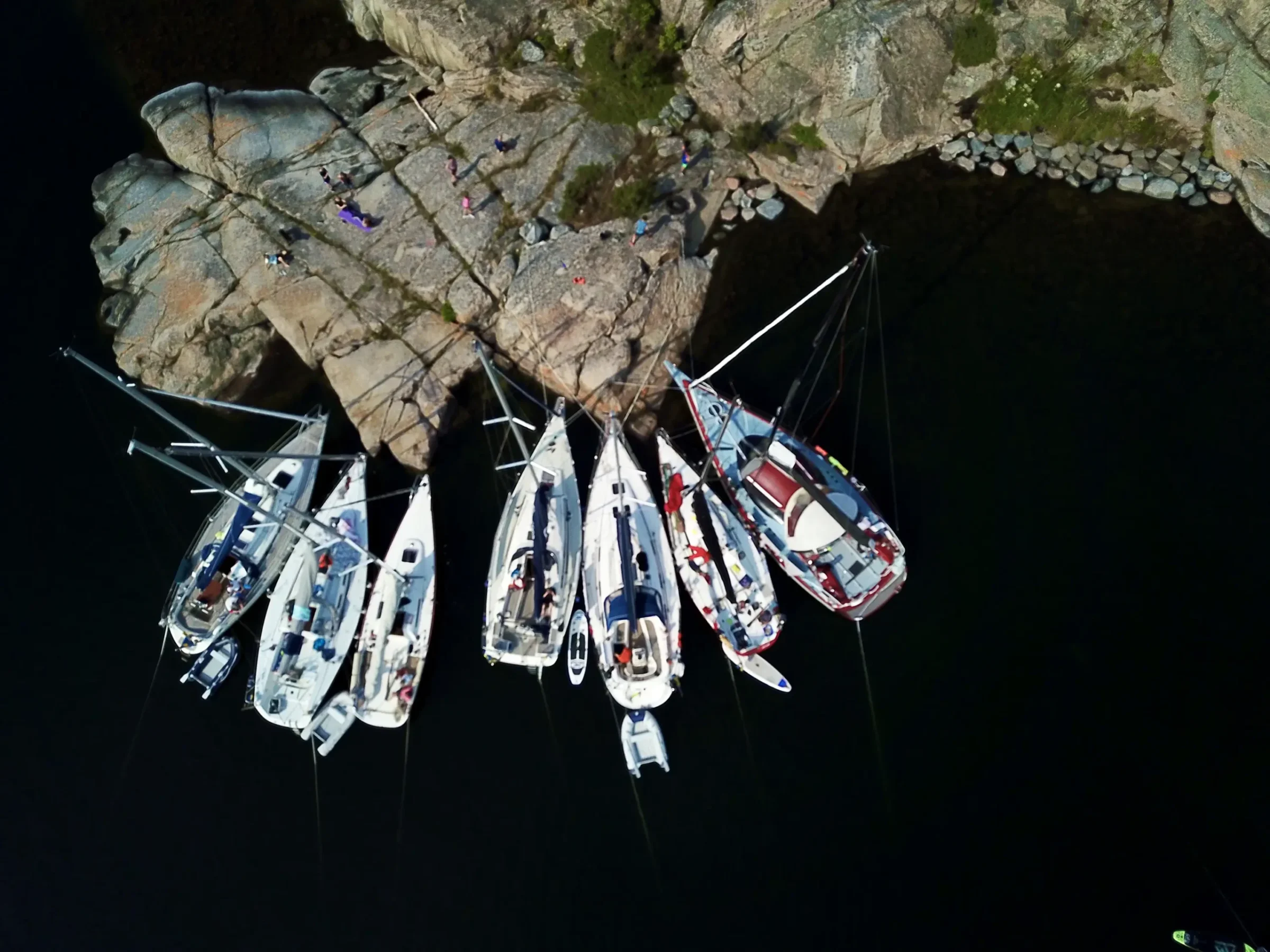 Flygfoto taget ovan 7 båtar vid en klippa.